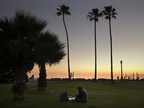 Sitting on the lawn at Doheny State Beach, Gholamreza Hagihgih, a 59-year-old Iranian immigrant who has been homeless for 20 years, eats his meal provided by a nonprofit organization Thursday, Dec. 21, 2017, in Dana Point, Calif. Goodhearted neighbors heartbroken over the rising number of homeless in their communities are dishing out hot meals, providing mobile showers and handing out sandwiches to those in need, hoping they can make a difference.