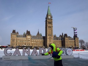 A worker spreads ice melter in front of the Canada 150 sign on Parliament Hill, in Ottawa, Friday December 29, 2017. Heritage Canada has announced an event will be canceled because of the extreme cold weather conditions leading up to News Years Day.