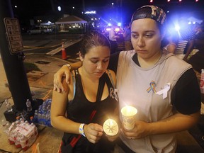 FILE - In this June 12, 2016, file photo, Sonia Parra, left, and Andrea Parra, who said they lost friends in the Pulse nightclub shooting, hold candles on the street corner near the nightclub in Orlando, Fla. In the five years since a gunman killed 20 children and six adults at the Sandy Hook elementary school in Newtown, Conn., the nation has seen a number of massacres topping the death toll from that shooting.