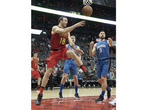 Atlanta Hawks center Miles Plumlee (18) sends a pass past Orlando Magic center Nikola Vucevic (9) as he saves a ball from going out of bounds during the first half of an NBA basketball game, Saturday, Dec. 9, 2017, in Atlanta.