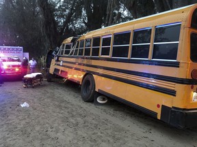 Authorities investigate the scene where a school bus crashed, Tuesday, Dec. 5, 2017, in Gum Branch, Ga. Liberty County Public Safety Director Mike Hodges said more than 20 children were riding the bus when it crashed  into a tree during its morning pick-up route.