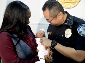 Savannah-Chatham police officer William Eng, right, plays with 29-day-old Bella Adkins while her mother, Tina Adkins, holds her on Monday, Dec. 4, 2017, at Savannah-Chatham police headquarters. Eng performed life-saving CPR on the infant on Friday.