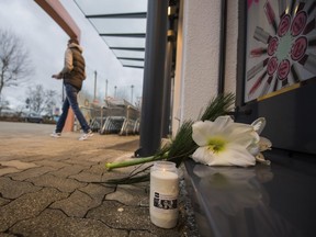 In this Dec. 27, 2017 photo. a customer leaves a drugstore in Kandel, Germany. Flowers and candles lie in front of the entrance. A 15-year-old Afghan asylum-seeker is in custody in Germany after allegedly fatally stabbing his ex-girlfriend, a German of the same age, in the drugstore. Police  say the stabbing followed what appeared to be an argument between the two Wednesday in Kandel, near the French border.