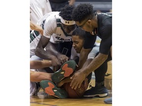 Both Hawaii and Miami players battle to control a loose basketball during the first half of an NCAA college basketball game at the Diamond Head Classic tournament, Friday, Dec. 22, 2017, in Honolulu.