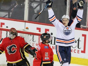 Flames goalie Mike Smith looks up as defenceman Mark Giordano skates by while the Edmonton Oilers' Jesse Puljujarvi celebrates his goal during first period action in Calgary on Saturday night.