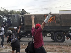 A soldier and a driver abandon their burning vehicle set on fire by protesters who ensue throwing rocks, in Tegucigalpa, Honduras, Friday Dec.15, 2017. Protests in support of Honduran presidential opposition candidate Salvador Nasralla continued throughout the country Friday as Nasralla demanded a full recount, refused to recognize the results and called for a nationwide protests.