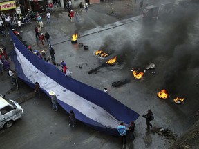 Supporters of presidential candidate Salvador Nasralla hold a Honduran flag as they block a road in Tegucigalpa, Honduras, Monday, Dec. 18, 2017. President Juan Orlando Hernandez has been declared the winner of Honduras' disputed election, but that isn't quelling unrest from weeks of uncertainty as his main challenger calls for more protests Monday and vows to take his claims of fraud to the OAS.