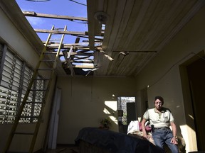 In this Nov. 15, 2017 photo, Edgardo de Leun sits in his living room with a hole in the ceiling caused by the whip of hurricane Maria in Puerto Rico.