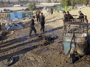 Afghan security forces inspect the site of a deadly bombing in Jalalabad province, east of Kabul, Afghanistan, Sunday, Dec. 31, 2017. Officials say the bombing targeted the funeral of a local official in eastern Afghanistan, killing at least 15 people and wounding over a dozen others.