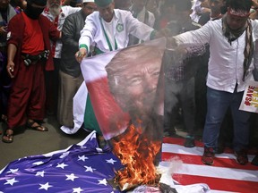 Protesters burn a poster of U.S. President Donald Trump during a rally outside the U.S. Embassy in Jakarta, Indonesia, Monday, Dec. 11, 2017. Hundreds of people staged the protest in the Indonesian capital of Jakarta to denounce Trump's decision to recognize Jerusalem as Israel's capital.