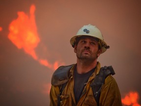 In this photo provided by the Santa Barbara County Fire Department, county fire hand crew member Nikolas Abele keeps an eye on a hillside for any stray embers during a firing operation in Santa Monica Canyon in Carpinteria, Calif., Monday, Dec. 11, 2017. Ash fell like snow and heavy smoke had residents gasping for air Monday as a wildfire exploded in size, becoming the fifth largest in state history.