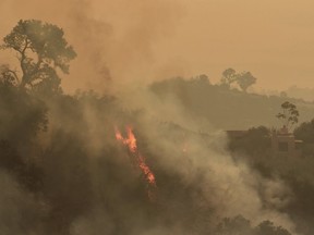 In this photo provided by the Santa Barbara County Fire Department, pockets of unburned vegetation flare up off Bella Vista Dr. in Montecito, Calif., Wednesday, Dec. 13, 2017. After announcing increased containment on the Thomas fire, one of the biggest wildfires in California history, officials Wednesday warned that communities remain at risk and the threat could increase as unpredictable winds whip up again.