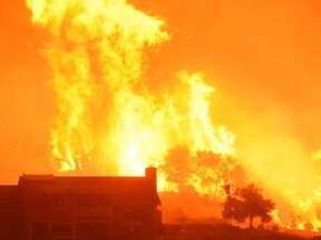 In this Sunday, Dec. 10, 2017 photo released by Santa Barbara County Fire Department, flames advance on homes off Shepard Mesa Road at 5:45 Sunday morning in Carpinteria, Calif. A flare-up on the western edge of Southern California's largest and most destructive wildfire sent residents fleeing Sunday, as wind-fanned flames churned through canyons and down hillsides toward coastal towns. Crews with help from water-dropping aircraft saved several homes as unpredictable gusts sent the blaze churning deeper into foothill areas northwest of Los Angeles that haven't burned in decades. New evacuations were ordered in Carpinteria, a seaside city in Santa Barbara County that has been under fire threat for days.