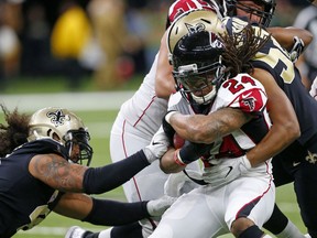 Atlanta Falcons running back Devonta Freeman (24) is tackled by New Orleans Saints outside linebacker Craig Robertson (52) and outside linebacker Hau'oli Kikaha, left, in the first half of an NFL football game in New Orleans, Sunday, Dec. 24, 2017.