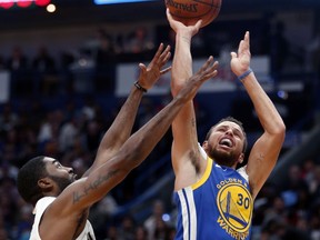 Golden State Warriors guard Stephen Curry (30) shoots over New Orleans Pelicans guard E'Twaun Moore in the first half of an NBA basketball game in New Orleans, Monday, Dec. 4, 2017.