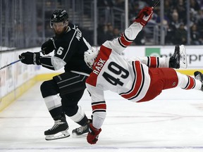 Los Angeles Kings defenseman Jake Muzzin, left, knocks Carolina Hurricanes center Victor Rask, of Sweden, off his skates with a check during the first period of an NHL hockey game in Los Angeles, Saturday, Dec. 9, 2017.