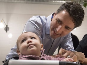 Prime Minister Justin Trudeau smiles towards a baby as speaks to people as they eat breakfast at Hometown Dinner in Saskatoon on Friday, December 8, 2017.