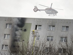 A helicopter flies over a high-rise building where a fire broke out, injuring more than a dozen people in Berlin, Germany, Saturday, Dec. 2, 2017.