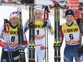 Second placed Maiken Caspersen Falla of Norway, first placed Stina Nilsson of Sweden, and third placed Kikkan Randall of the US, pose for photographers in the finish area after the sprint final run at the cross country World Cup in Davos, Switzerland, on Saturday, Dec. 9, 2017.
