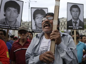 A demonstrators shouts slogans against pardon of former President Alberto Fujimori with photographs of the nine university students who were kidnapped, killed and disappeared in 1992 by the undercover military group Colina, in Lima, Peru, Monday, Dec. 25, 2017. Peru's President Pedro Pablo Kuczynski announced Sunday night that he granted a medical pardon to the jailed former strongman who was serving a 25-year sentence for human rights abuses, corruption and the sanctioning of death squads.