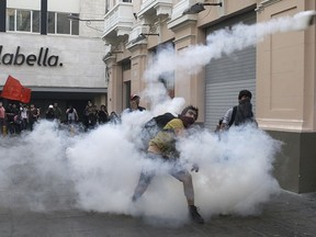 A demonstrators throws a tear gas canister back towards the police during clashes against the pardon of former President Alberto Fujimori in Lima, Peru, Monday, Dec. 25, 2017. Peru's President Pedro Pablo Kuczynski announced Sunday night that he granted a medical pardon to the jailed former strongman who was serving a 25-year sentence for human rights abuses, corruption and the sanctioning of death squads.