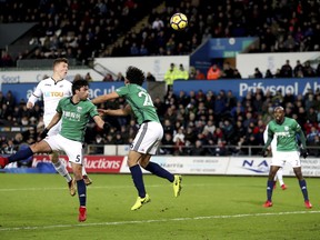 Swansea City's Alfie Mawson, left, heads the ball over the bar during their English Premier League soccer match against West Bromwich Albion at the Liberty Stadium, Swansea, Wales, Saturday, Dec. 9, 2017.