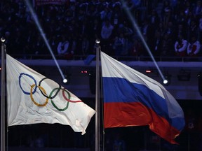 FILE - In this Feb. 23, 2014 file photo, the Russian national flag, right, flies next to the Olympic flag during the closing ceremony of the 2014 Winter Olympics in Sochi, Russia. The word "Russia" will appear on the Olympic uniforms worn by the athletes granted an exemption from the country's doping ban. More than 200 athletes are set to compete in Pyeongchang as an "Olympic Athlete from Russia" if they can prove they aren't tainted by doping.