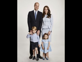 In this undated photo provided by Kensington Palace on Monday, Dec. 18, 2017, Britain's Prince William, background left and Kate, the Duchess of Cambridge pose with their children Prince George and Princess Charlotte, at Kensington Palace. The photo has been used on the Cambridges' Christmas card.