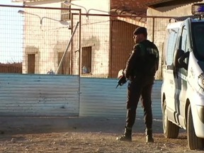 In this image taken from video a member of Spain's Civil Guard stands outside a house near Canatvieja Spain on Friday Dec. 15, 2017. Spanish authorities  arrested a homicide suspect wanted for months by Italy after three people were killed in Spain, including two Civil Guards. Norbert Feher, a 36 year-old from Serbia, was arrested  at the house overnight near Cantavieja, a town in northeastern rural Spain, after he allegedly shot and killed a civilian and two Civil Guard police Thursday. Italy had issued a European arrest warrant for Feher for homicides and home invasion robberies.(Atlas via AP)