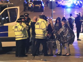 FILE - This s a May 23, 2017 file photo of members of the  emergency services  attending the scene at Manchester Arena after reports of an explosion at the venue during an Ariana Grande gig. An independent review of the counter-terrorism performance by British police and intelligence services rleease on Tuesday Dec. 5, 2017  suggested that the deadly suicide bombing at Manchester Arena might have been prevented if information had been handled differently.