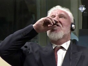 In this photo provided by the ICTY on Wednesday, Nov. 29, 2017, Slobodan Praljak brings a bottle to his lips, during a Yugoslav War Crimes Tribunal in The Hague, Netherlands. Praljak yelled, "I am not a war criminal!" and appeared to drink from a small bottle, seconds after judges reconfirmed his 20-year prison sentence for involvement in a campaign to drive Muslims out of a would-be Bosnian Croat ministate in Bosnia in the early 1990s. (ICTY via AP)