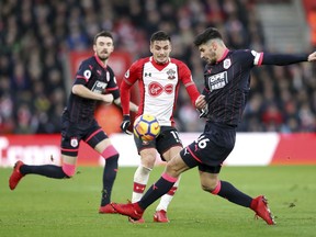 Southampton's Dusan Tadic, centre and Huddersfield Town's Christopher Schindler battle for the ball, during the English Premier League soccer match between Southampton and Huddersfied at St Mary's, in Southampton, England, Saturday, Dec. 23, 2017.
