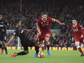 Liverpool's Adam Lallana and Swansea City's Kyle Naughton, left, battle for the ball during the English Premier League soccer match at Anfield, Liverpool, England, Tuesday Dec. 26, 2017.