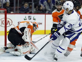 Flyers goaltender Brian Elliott, left, covers up the shot attempt by Toronto Maple Leafs' Dominic Moore during the first period of their game Tuesday night in Philadelphia.