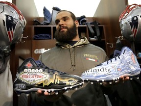 In this Wednesday, Nov. 29, 2017, photo New England Patriots defensive end Lawrence Guy displays cleats that honor victims of the Oct. 2017 Las Vegas shooting, left, and families who have lost an infant, right, in the team's locker room following an NFL football practice, in Foxborough, Mass. Guy will honor both causes on the field this weekend during the NFL's My Cause, My Cleats initiative.