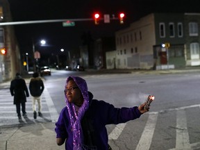 In this Dec. 14, 2017 photo, Erricka Bridgeford spreads sage as she performs a ceremony near the scene of a homicide in Baltimore. Bridgeford leads near-daily ceremonies in an effort to transform murder sites into places of inspiration. Bridgeford is a professional conflict mediator and the main organizer behind "Baltimore Ceasefire."