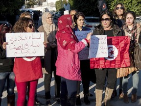 Tunisian women stage a protest near the United Arab Emirates' embassy in Tunis, Tunisia, Monday Dec. 25, 2017. Tunisia has suspended all flights by Emirates to and from Tunis after the Dubai-based airline barred Tunisian women from boarding its flights last week.