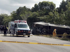 An ambulance sits parked next to an overturned bus in Mahahual, Quintana Roo state, Mexico, Tuesday, Dec. 19, 2017.