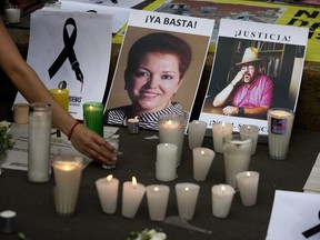 In this May 16, 2017 file photo, a woman places a candle in front of pictures of murdered journalists Miroslava Breach, left, and Javier Valdez during a demonstration against the killing of journalists, outside the Interior Ministry in Mexico City. More than three dozen Mexican media organizations announced Monday, Dec. 4, 2017 that they are joining forces to try to combat a wave of journalist killings in the country, including at least nine this year. (Rebecca Blackwell/AP Photo)