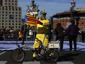 A man with an 'Estelada', the pro-independence Catalan flag, attached to his bicycle attends a concert in support of the politicians and civil leaders imprisoned at the Plaza Espanya square in Barcelona, Sunday, Dec. 3, 2017. A Spanish Supreme Court judge is set to decide on Monday if two Catalan pro-independence activists and eight former members of the separatist regional cabinet ousted over a month ago should be released from custody after hearing their appeal.