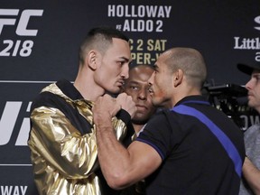 In a Thursday, Nov. 30, 2017 photo,  Max Holloway, left, faces Jose Aldo during media day for the UFC 218 mixed martial arts fight in Detroit. Holloway respects Aldo, saying he's one of the greatest ever in mixed martial arts but is hoping to play a part in beginning to end Aldo's career. The Hawaiian fighter beat Aldo in his native Brazil in June, earning the featherweight title, and he is aiming to do it again in a rematch at UFC 218 on Saturday in Detroit.
