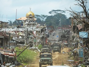 Military trucks drive past destroyed buildings and a mosque in what was the main battle area in Marawi on the southern island of Mindanao on Oct. 25, 2017.