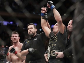 Georges St-Pierre, right, celebrates after defeating Michael Bisping to win the UFC's middleweight title in November.
