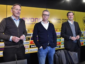 Borussia Dortmund CEO Hans-Joachim Watzke, left, and sporting manager Michael Zorc, right, present Austrian coach Peter Stoeger, center, as the new head coach of the Bundesliga soccer club at a press conference in Dortmund, Germany, Sunday, Dec. 10, 2017. Borussia Dortmund displaced Dutch head coach Peter Bosz on Saturday after a defeat against Werder Bremen. Stoeger was dismissed as head coach of FC Cologne earlier this month.