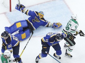 St. Louis Blues goalie Jake Allen, top left, falls while reaching for a puck as Dallas Stars' Gemel Smith (46) watches during the first period of an NHL hockey game Thursday, Dec. 7, 2017, in St. Louis.