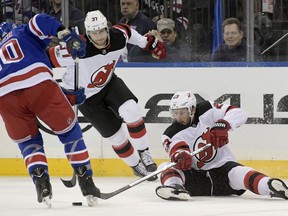New Jersey Devils right wing Stefan Noesen (23) attempts to get his stick on the puck as New York Rangers left wing J.T. Miller (10) and Devils center Pavel Zacha (37) close in during the first period of an NHL hockey game Saturday, Dec. 9, 2017, at Madison Square Garden in New York.