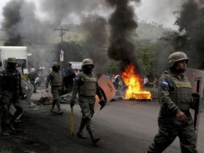 Soldiers walk past a flaming barricade set up by protestors supporting opposition presidential candidate Salvador Nasralla, in the outskirts of Tegucigalpa, Honduras, Friday, Dec. 22, 2017. The Trump administration on Friday recognized the results of Honduras' disputed presidential election despite opposition complaints, irregularities found by poll observers and calls from Congress to back a new vote.