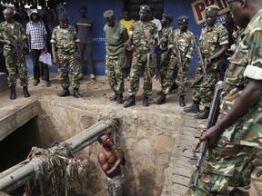FILE - In this Thursday, May 7, 2015 file photo, Jean Claude Niyonzima, a suspected member of the ruling party's Imbonerakure youth militia, pleads with soldiers to protect him from a mob of demonstrators after he came out of hiding in a sewer in the Cibitoke district of Bujumbura, Burundi. In Burundi, human rights activists have begun documenting a new target of the government's deadly security forces: members of the feared Imbonerakure youth group who are now killed to ensure their silence. (AP Photo/Jerome Delay, File)
