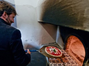 Italian Culture Minister Dario Franceschini cooks a pizza in the first stone oven which was used in the 1889 to make the first pizza Margherita in Naples, Italy, Wednesday, Dec. 6, 2017. Italy is waiting a decision by the United Nations Educational, Scientific and Cultural Organisation (UNESCO) to recognize to the Neapolitan pizza in the intangible cultural heritage list.