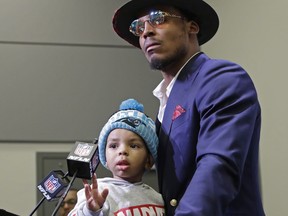 Carolina Panthers' Cam Newton listens to a question from the media with his son Chosen, 2, after an NFL football game against the Tampa Bay Buccaneers in Charlotte, N.C., Sunday, Dec. 24, 2017.